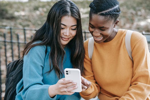 Cheerful multiethnic women browsing smartphone in park